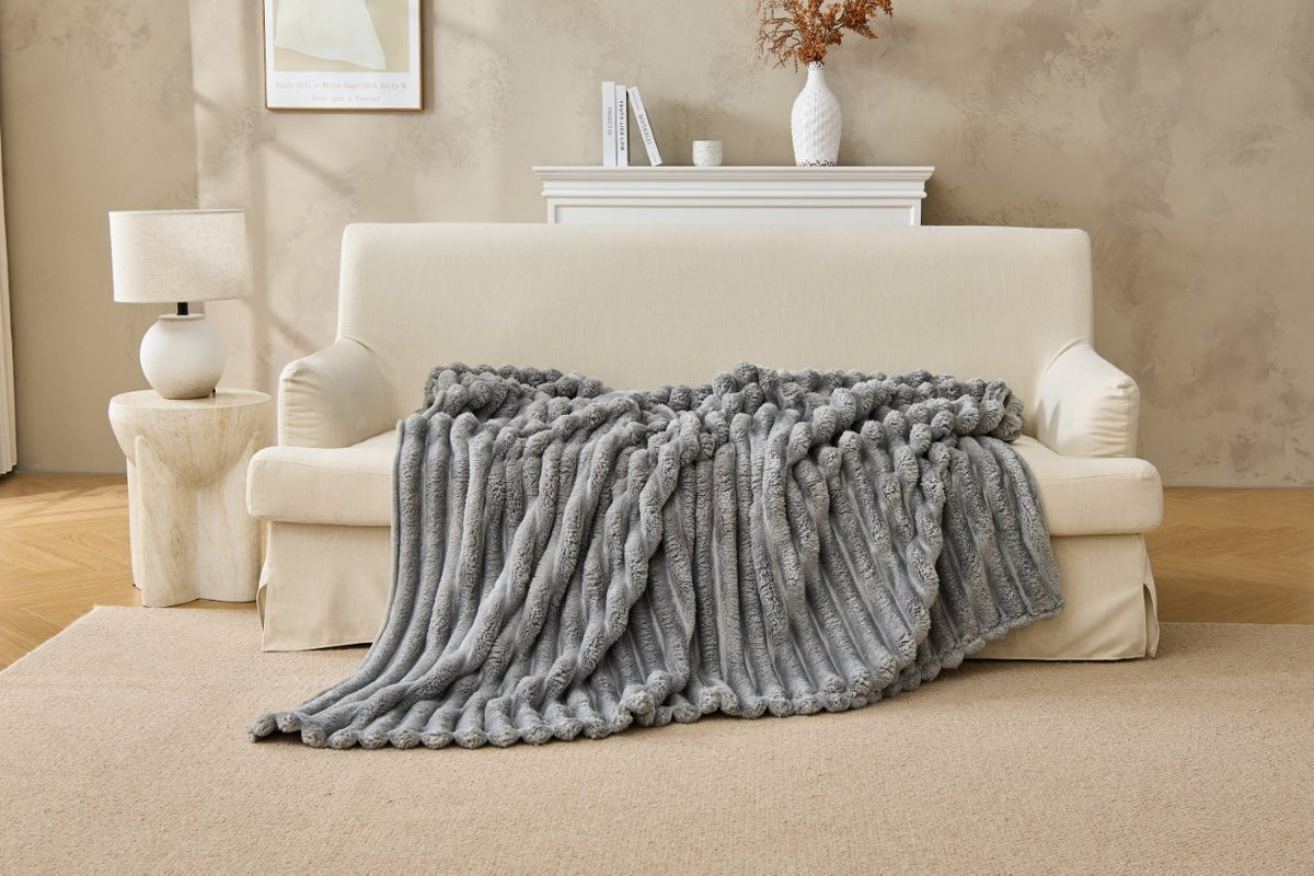 Black chunky fleece throw draped over a modern sofa
