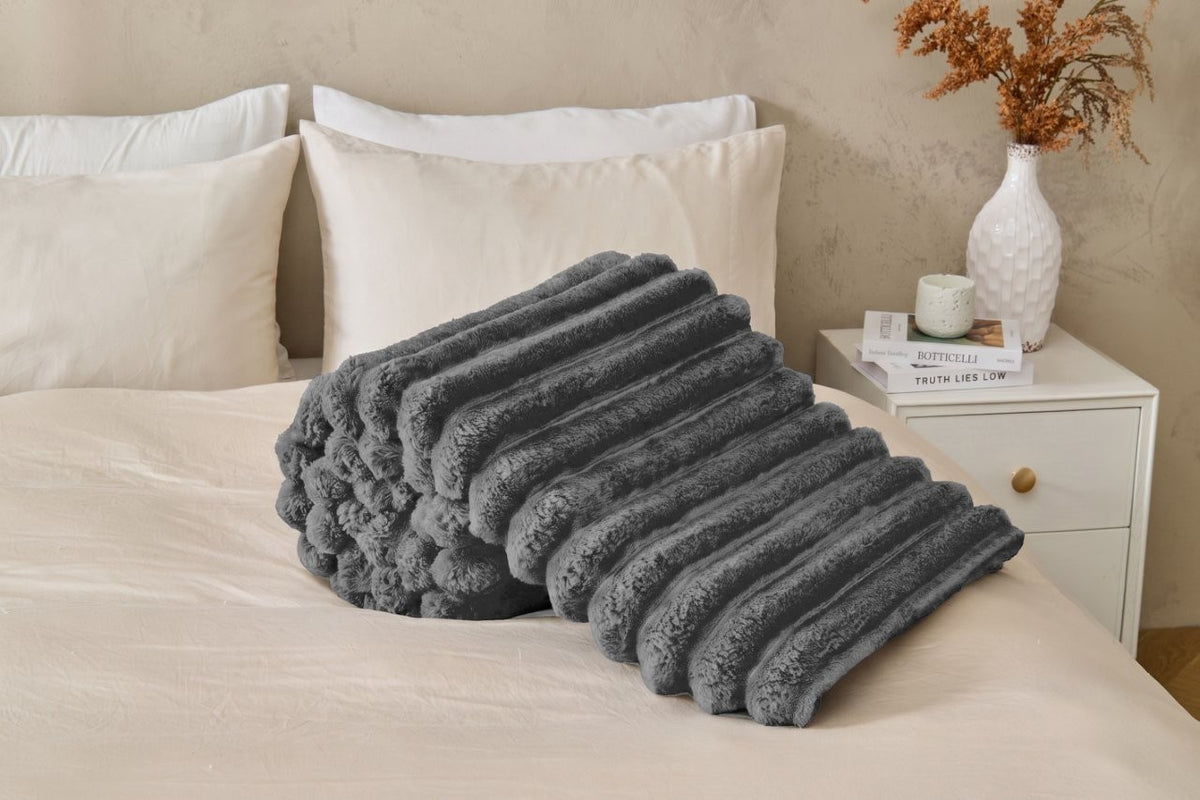 Navy chunky fleece throw folded on the end of a sofa