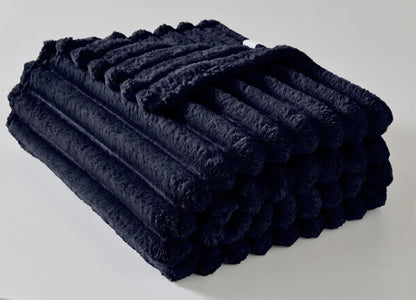 Person wrapped in a ribbed fleece throw on the sofa for movie night
