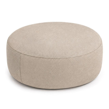 Beige round inflatable pouffe used as a footrest in a living room