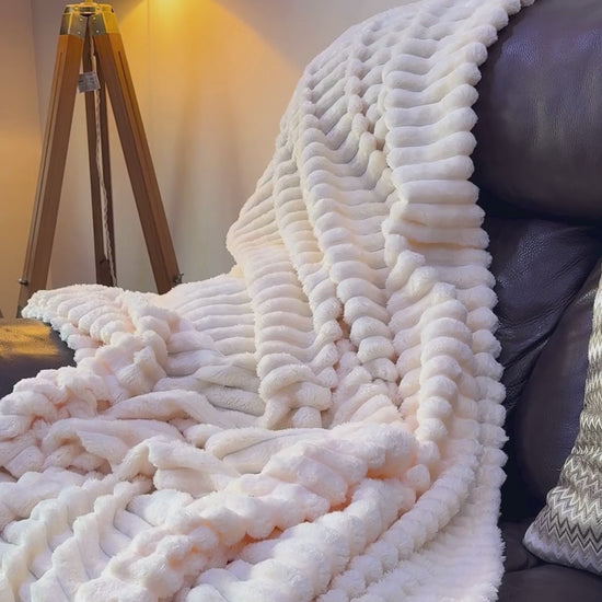 Large ribbed corded throw blanket draped over sofa – chunky cord faux fur fleece in double and king size