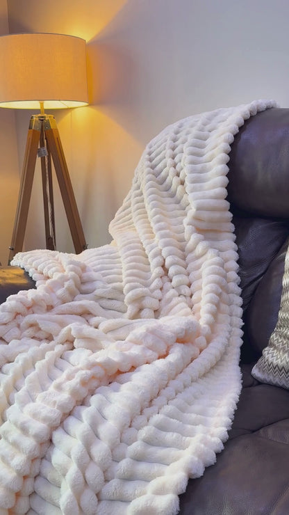 Large ribbed corded throw blanket draped over sofa – chunky cord faux fur fleece in double and king size