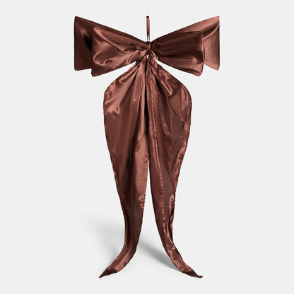 Chocolate Christmas bow close-up showing satin sheen and flowing tails