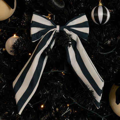 Black striped Christmas bow hanging on tree branch detail