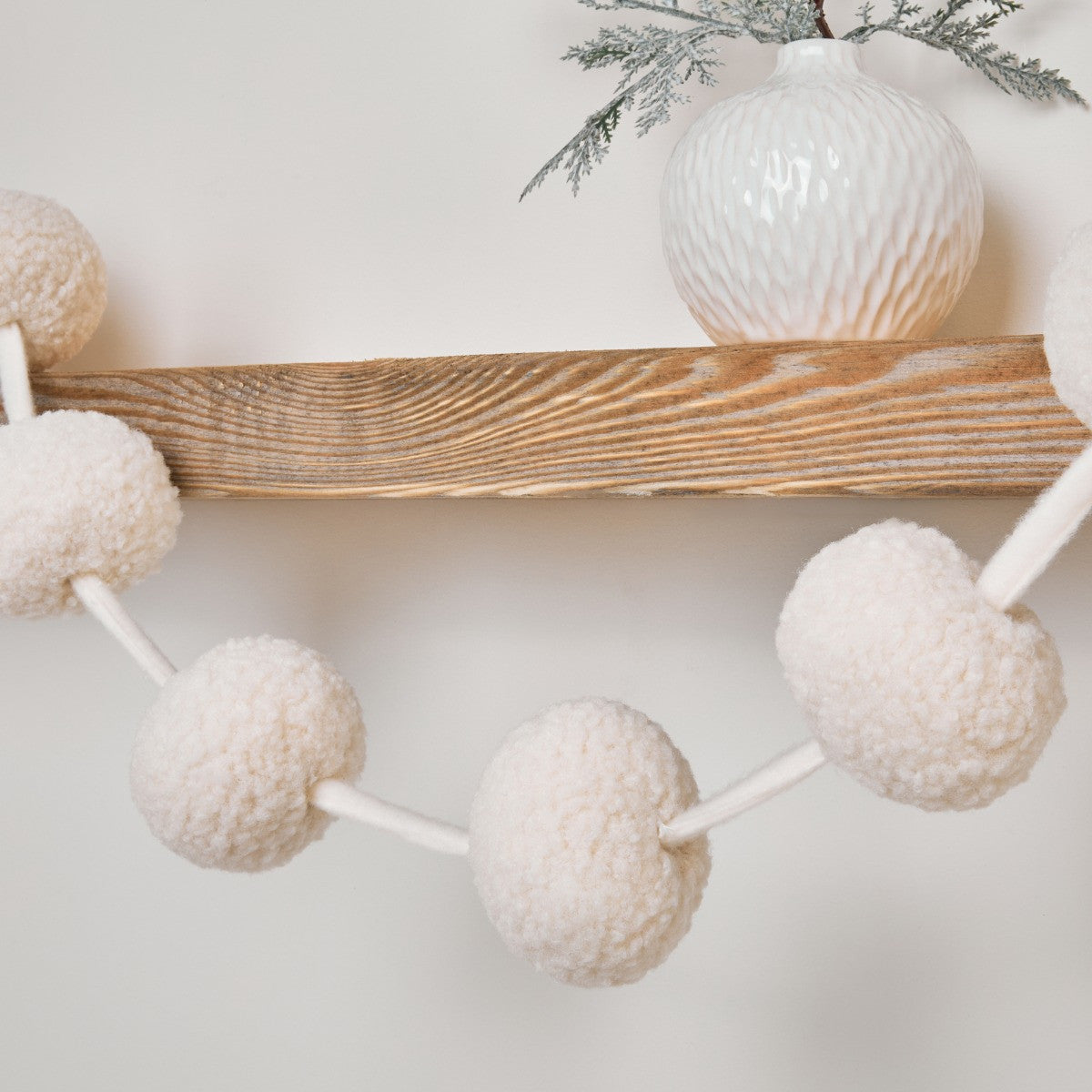 Cream pom pom garland draped on mantelpiece - festive decor