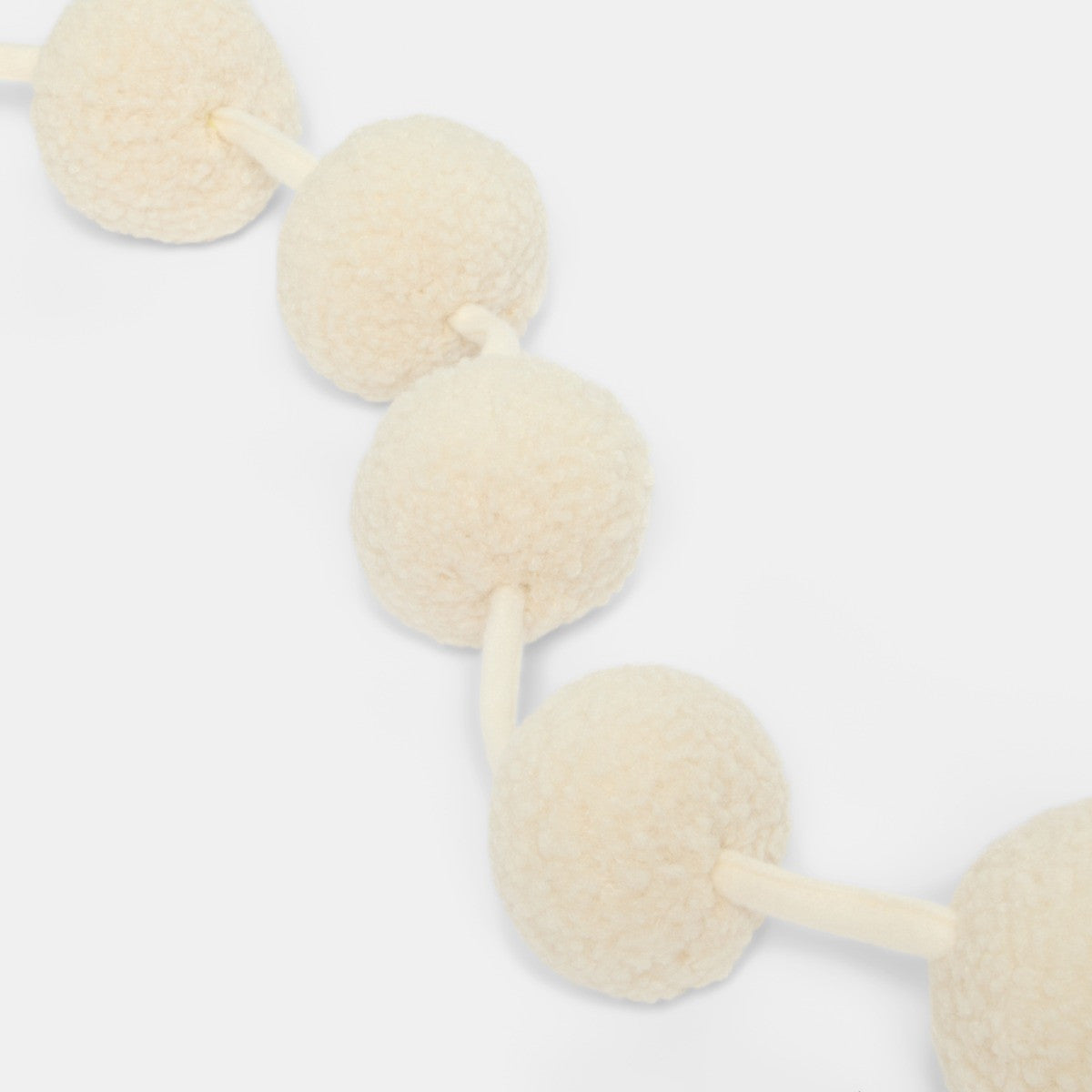 Cream pom pom tree decoration styled on branch - boho Christmas