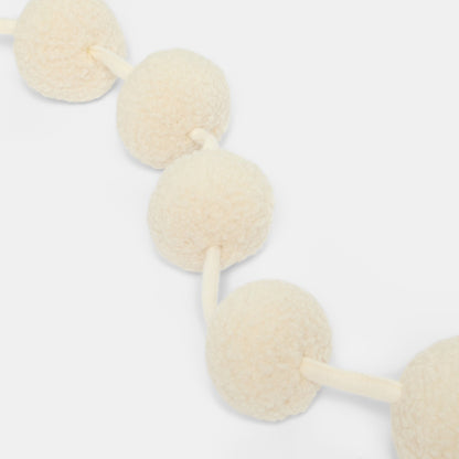Cream pom pom tree decoration styled on branch - boho Christmas